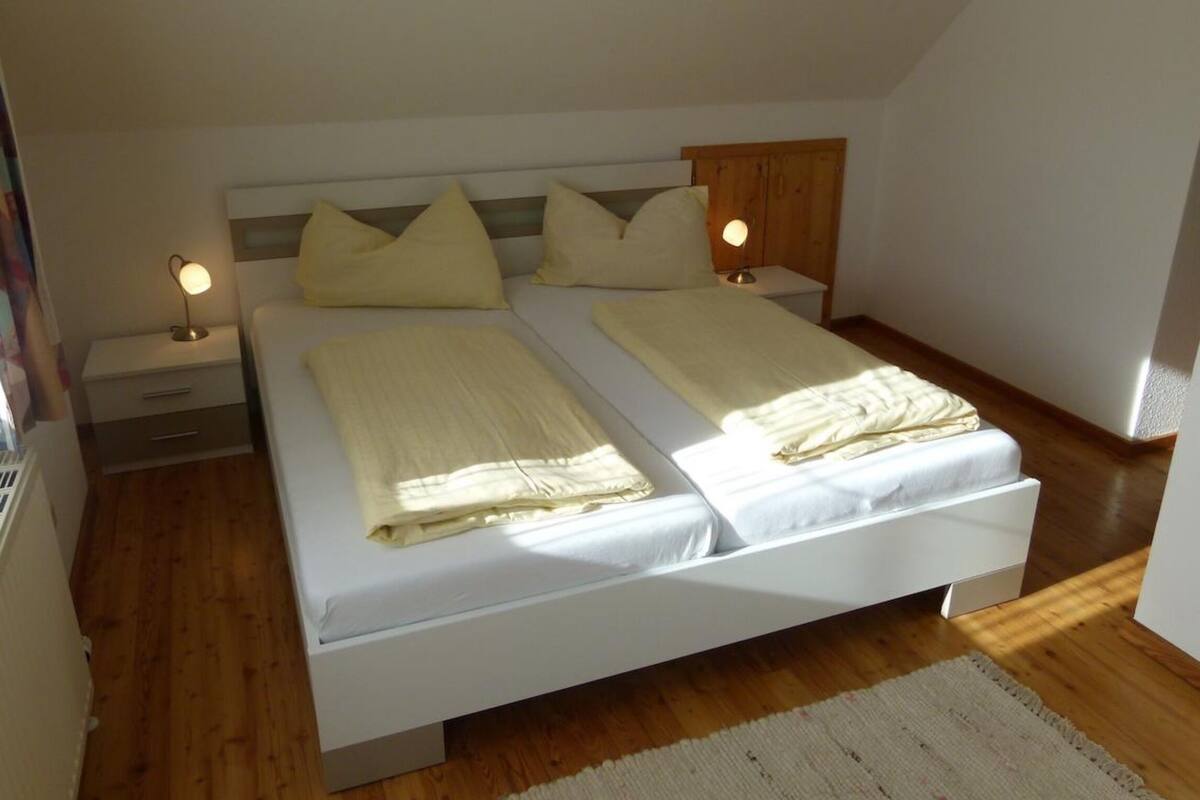 Un dormitorio con una cama, dos mesitas de noche y una mesita auxiliar.