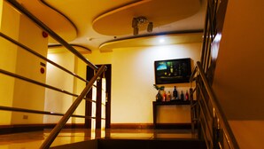 Eine Treppe mit Handlauf, einem an der Wand befestigten Fernseher und einem Regal mit Flaschen.