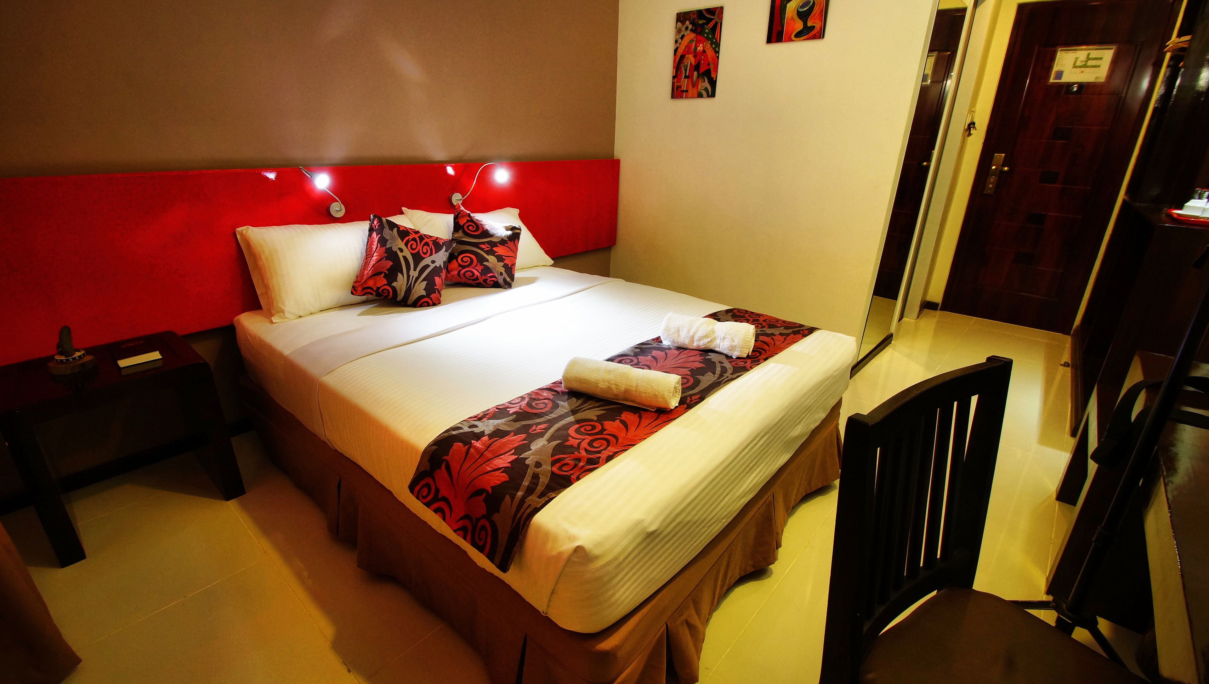 A hotel room with a bed, a nightstand, a chair, and a door.