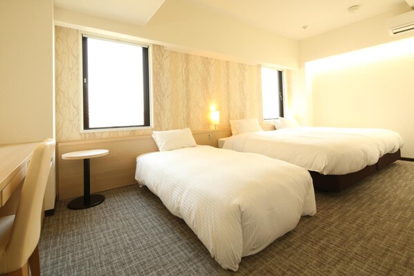 Habitación de hotel con dos camas, una mesita redonda y una ventana.