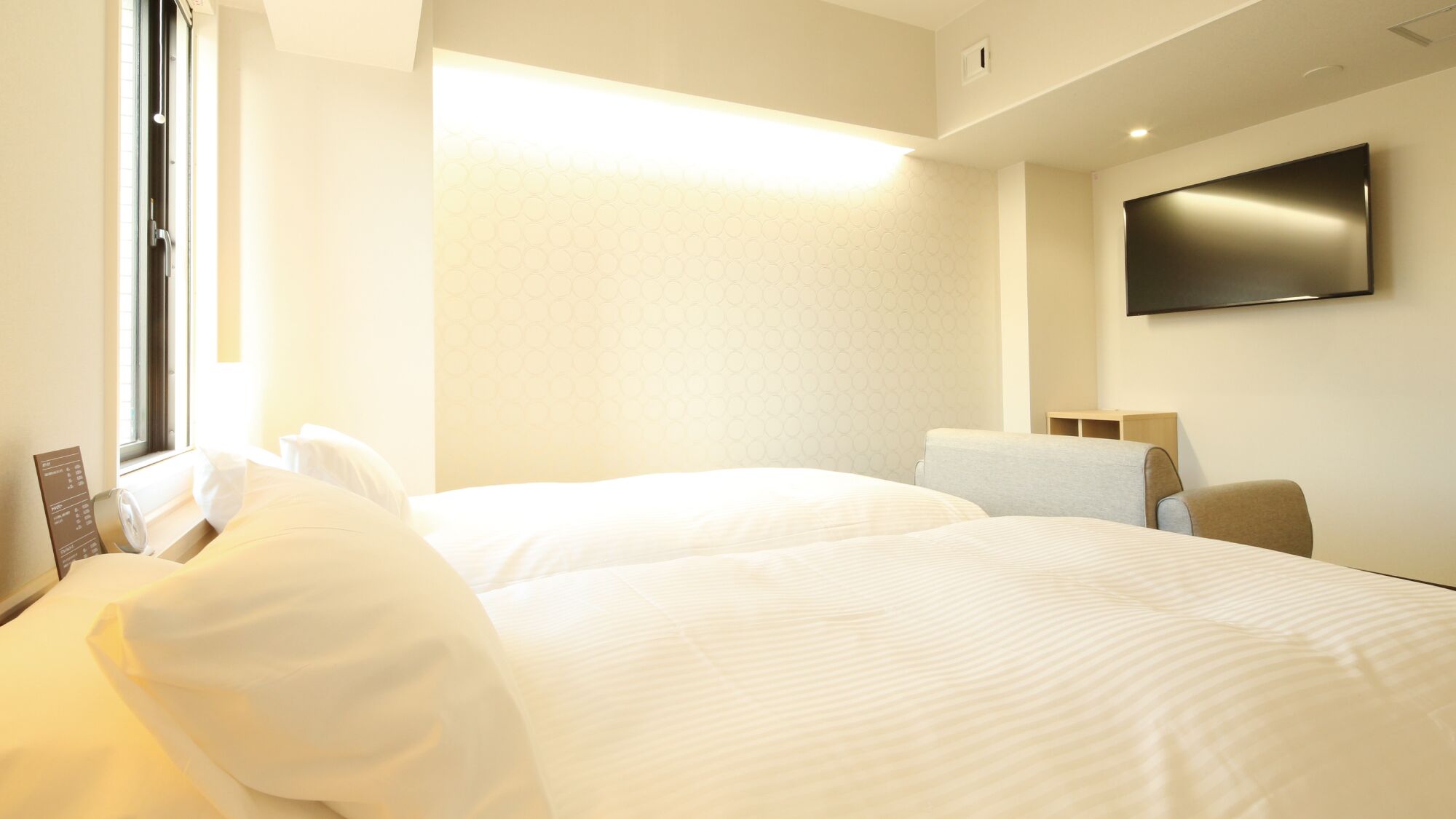 Een hotelkamer met twee bedden, een flatscreen televisie en een raam.