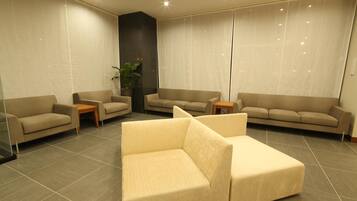 A modern living room with a sectional sofa, two armchairs, a coffee table, and a potted plant.