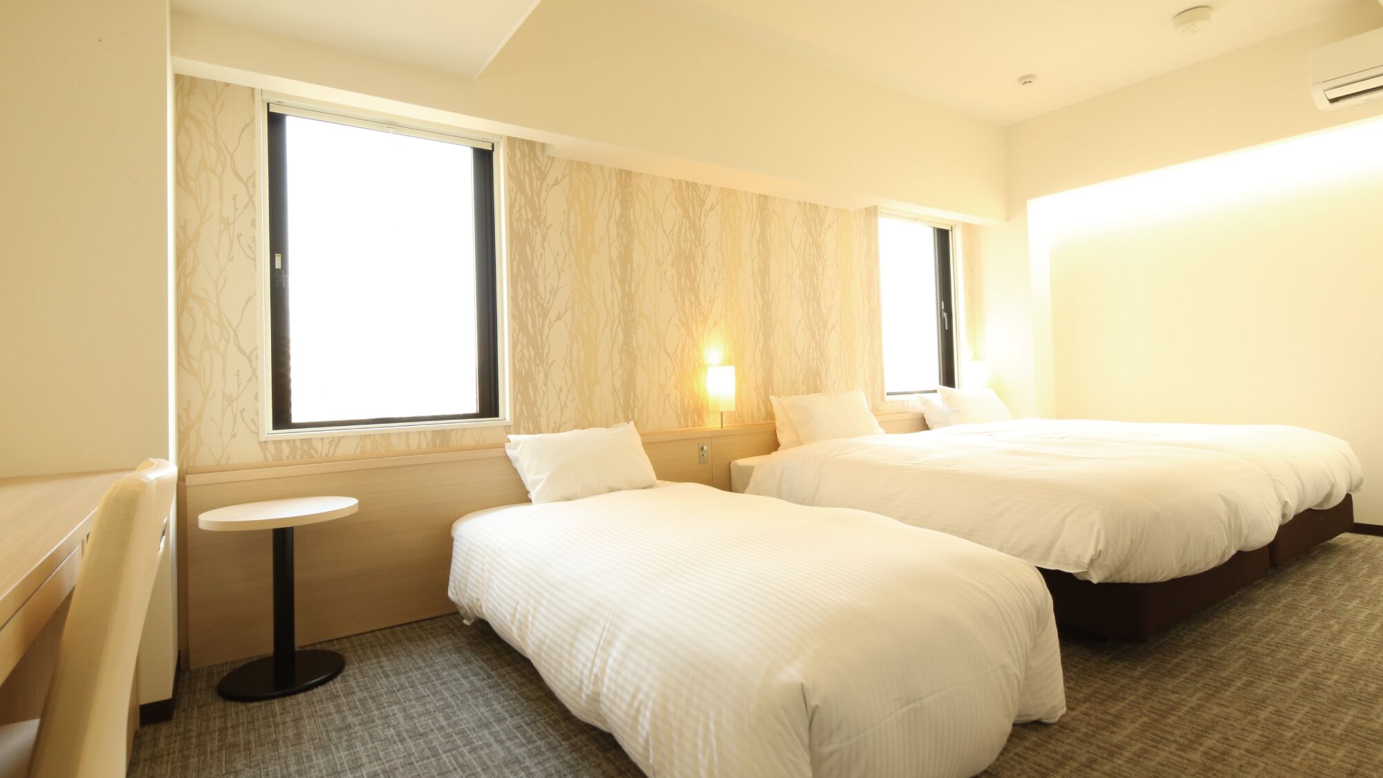 Een hotelkamer met twee bedden, een kleine tafel en een raam.