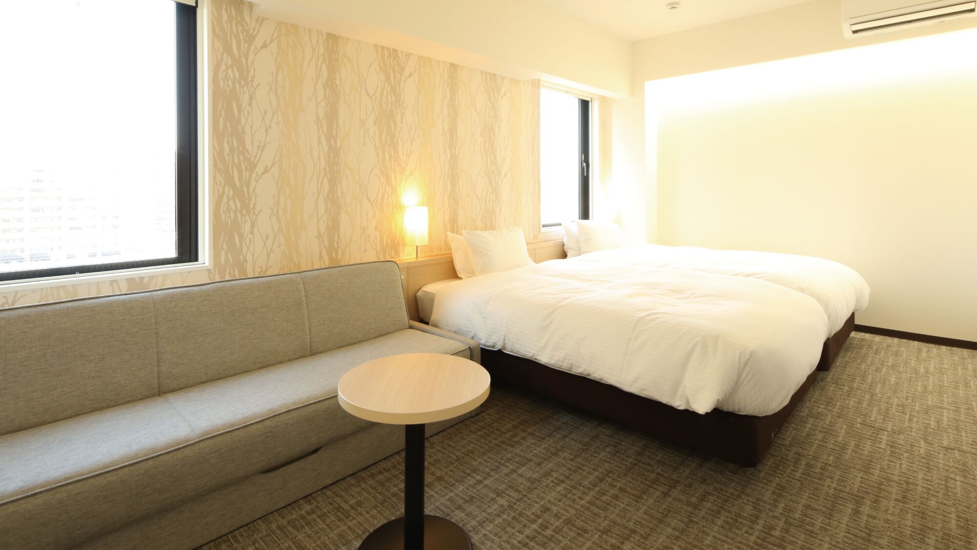 Een hotelkamer met een bed, een bank, een klein tafeltje en een raam.