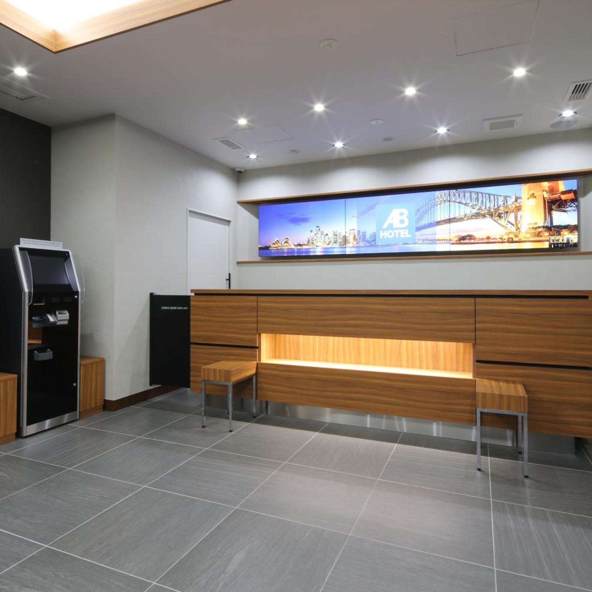 A hotel reception area with a digital display, a reception desk, and a seating area.