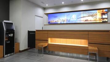 A hotel reception area with a digital display, a reception desk, and a seating area.