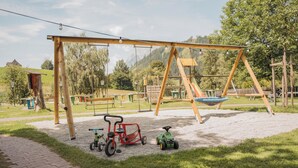 A playground with swings, a slide, and tricycles.