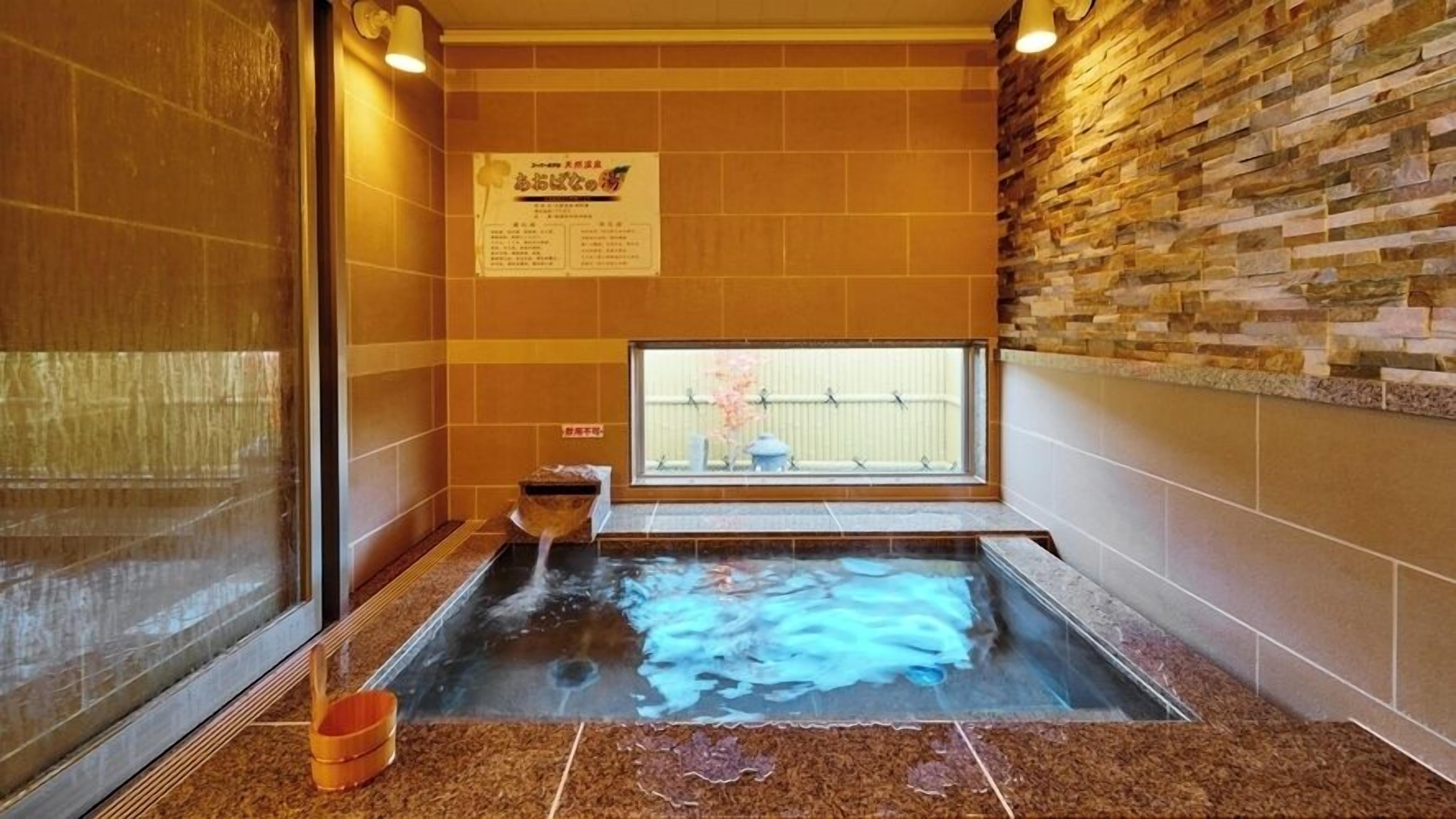 A hot spring bath with a stone wall, a window, and a sign.