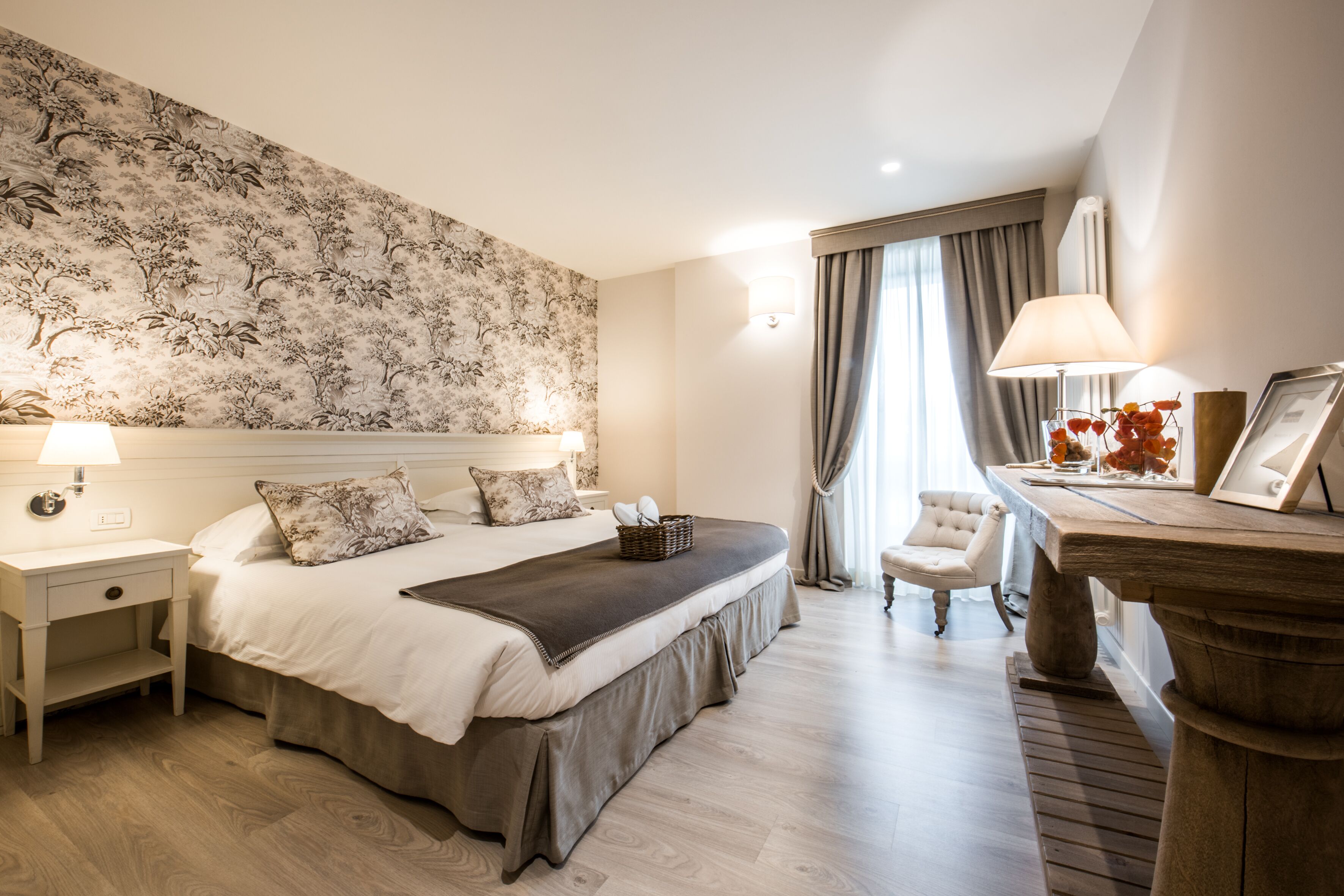A hotel room with a large bed, bedside tables, a desk, and a chair.