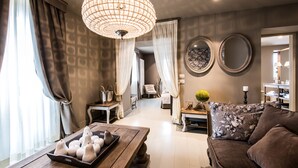 A modern living room with a wooden coffee table, a brown sofa, and a chandelier. - Meltar Boutique Hotel (Asiago)