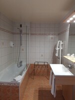 A bathroom with a bathtub, a shower, a sink, and a towel rack.