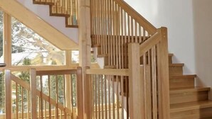 Una escalera de madera con alfombra de estampado rojo que lleva a un balcón.