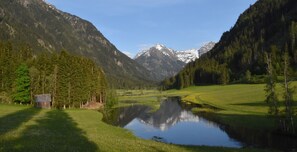 A serene mountain landscape with a clear lake, a small wooden cabin, and lush greenery. - Gasthof Tetter (Schladming)