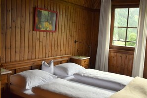 A wooden room with a bed, a nightstand, a lamp, and a window with curtains. - Gasthof Tetter (Schladming)