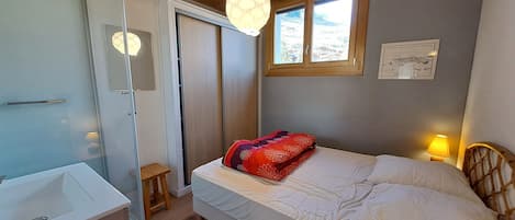 Un dormitorio con cama, mesita de noche, lámpara y ventana con vistas.