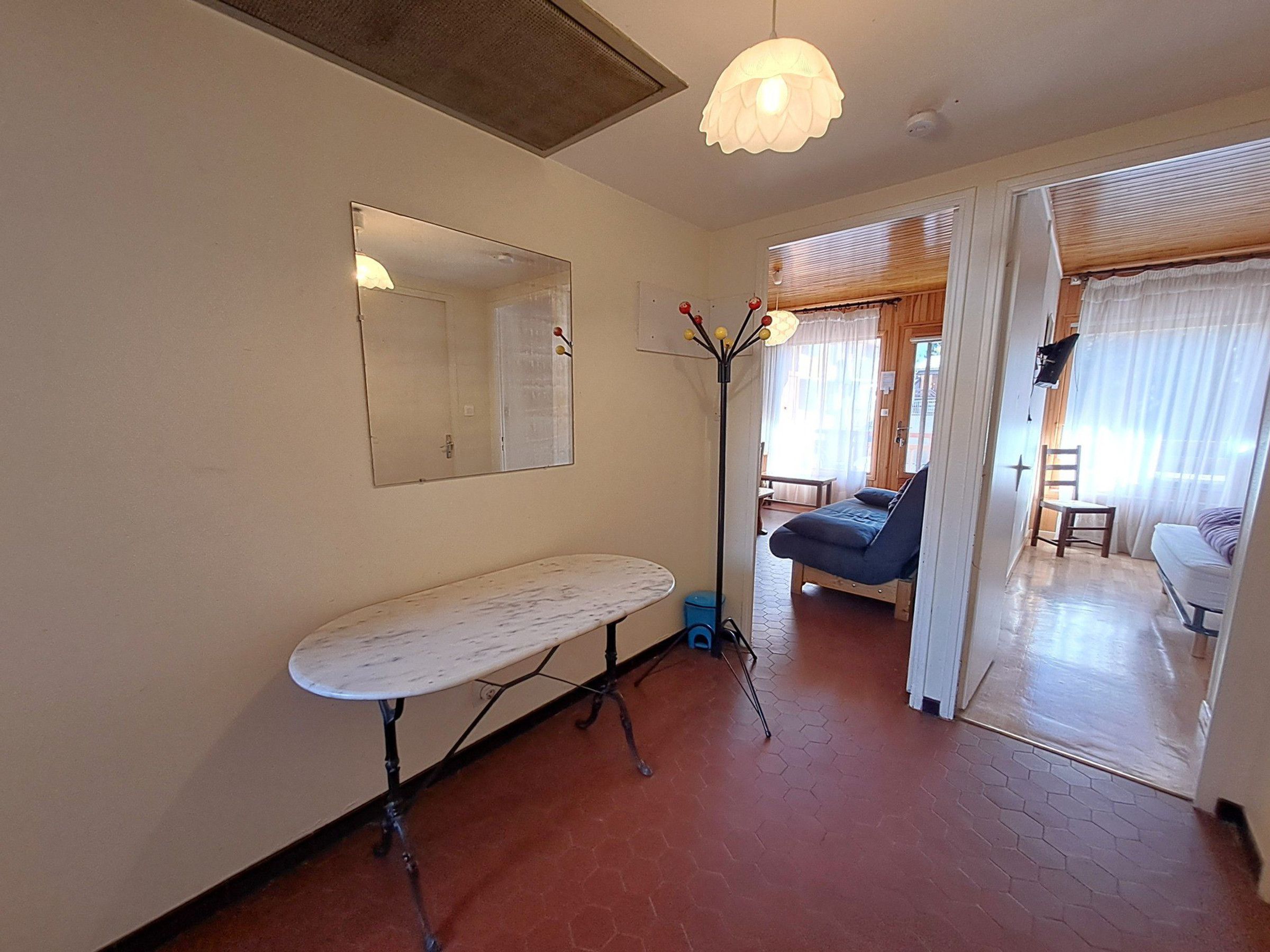 A room with a bed, a chair, a table, a mirror, and a floor lamp.