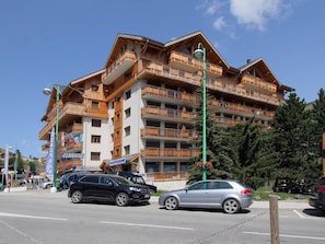A multi-story hotel with wooden balconies and a ski resort sign. - Apartment 8 guests, near slopes, pets allowed (Les Deux Alpes)