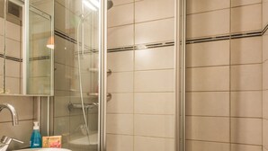 Ein Badezimmer mit Waschbecken, Spiegel, Dusche und Pflegeprodukten.