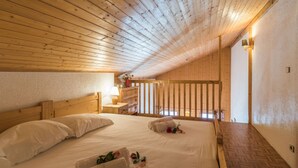 Ein Schlafzimmer mit Holzboden, einem Bett mit weißer Bettwäsche, einem Nachttisch und einem kleinen Tisch mit Lampe.