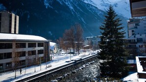Ein verschneiter Bahnhof mit Blick auf schneebedeckte Berge im Hintergrund.