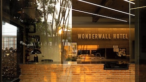 Un mur de briques sur lequel est inscrit « WONDERWALL HOTEL » et un comptoir d’accueil.