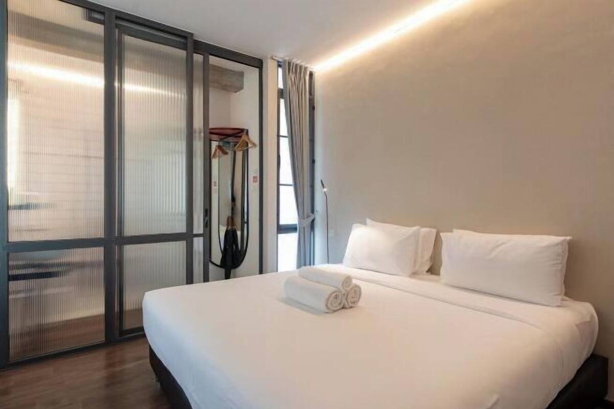 A hotel room with a large bed, a sliding glass door, and a coat rack.