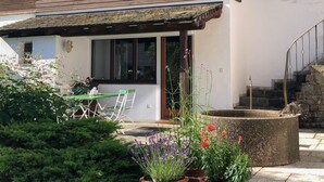 A two-story house with a balcony, a small garden with potted plants, and a staircase leading to the upper floor. - Apartment "Am Berg" in Fischbachau, Birkenstein (Fischbachau)