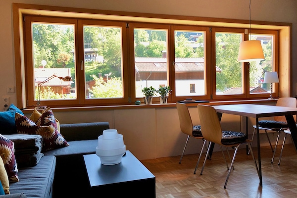 Fensterfront im Wohnzimmer mit Blick in den Garten und in die Berge