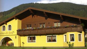 A yellow building with a wooden balcony, a sign reading "Gasthof St. Georg," and a mountainous backdrop. - Landhaus St. Georg (Sankt Martin am Tennengebirge)