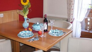 A dining table set with blue and white plates, a vase with a sunflower, a bottle of wine, and a glass. - Landhaus St. Georg (Sankt Martin am Tennengebirge)