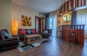 A modern living room with a sofa set, a coffee table, and a bar area with stools. - Vivid Vera Apartments (Tbilisi)