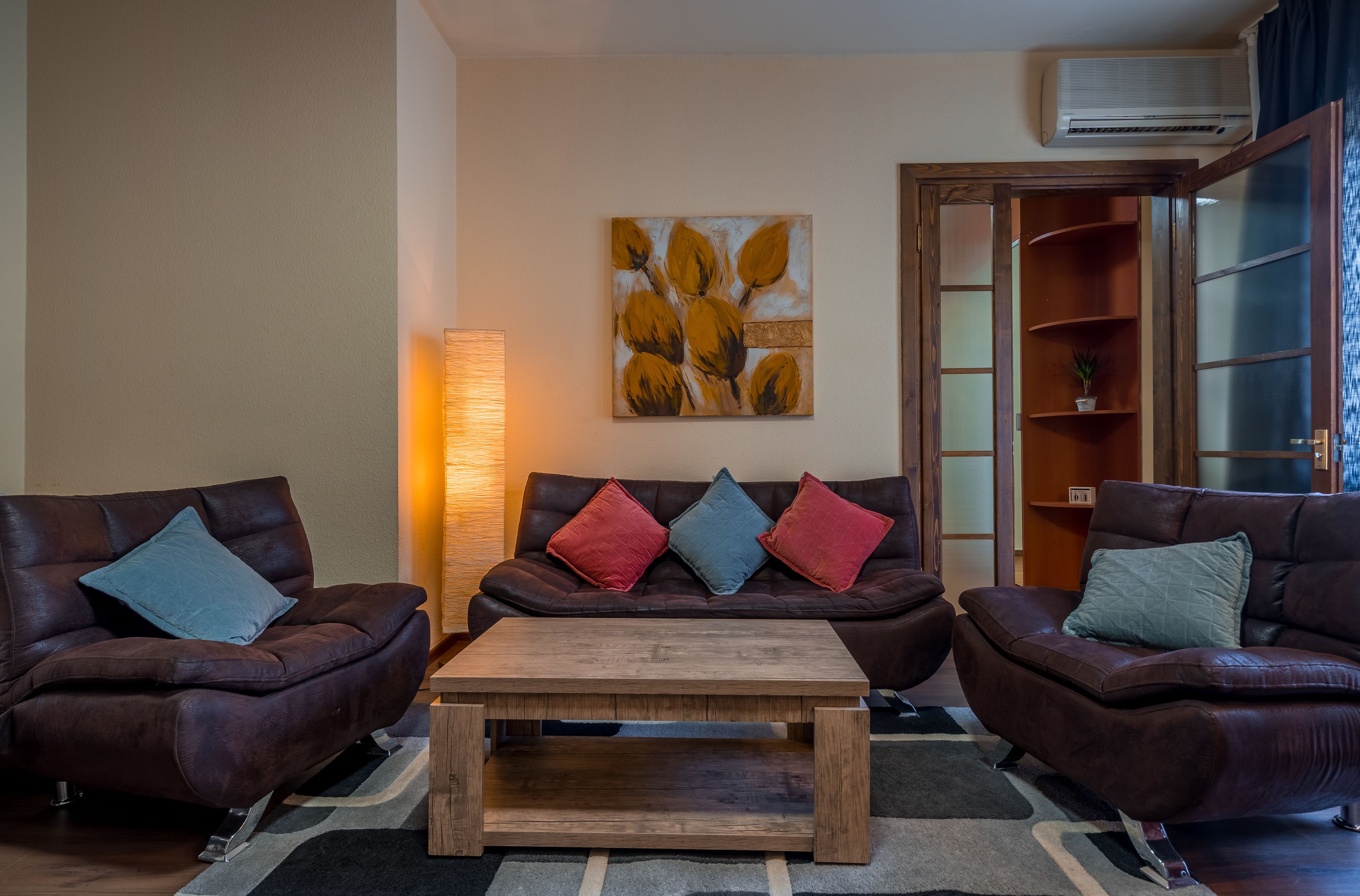 A living room with two leather sofas, a wooden coffee table, and a painting on the wall.