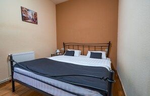 A single bed with a metal frame, white bedding, and two black pillows. - Vivid Vera Apartments (Tbilisi)