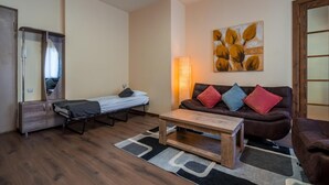 Un espacio habitable compacto con una cama, un sofá, una mesita de centro y un espejo grande.