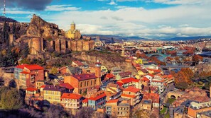 A historic town with a prominent castle on a hill, surrounded by colorful buildings and a river. - Vivid Vera Apartments (Tbilisi)