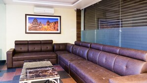 Een moderne woonkamer met een hoekbank, een marmeren salontafel en een schilderij van een stadsgezicht aan de muur.
