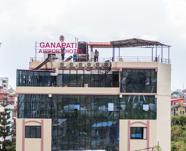 Experience the modern design of Ganapati Airport Hotel, featuring large windows and a covered area for taking in the view.