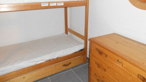 Ein Stockbett mit Holzbettrahmen und eine Kommode mit Schubladen.