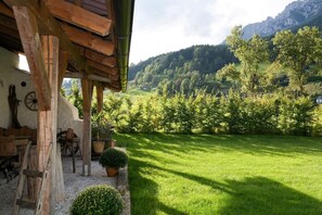 Un bâtiment rustique en bois, doté d’un mur en pierre, d’une table en bois et de chaises à l’extérieur.
