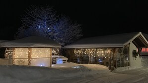 A snow-covered building with a glass structure and string lights. - Tischlmuehle Appartements & mehr (Mitterberg-Sankt Martin)