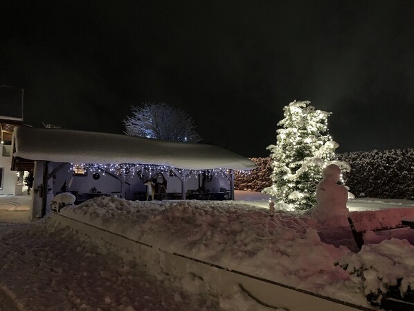A snow-covered outdoor area with a covered seating area and a snowman statue. - Tischlmuehle Appartements & mehr (Mitterberg-Sankt Martin)