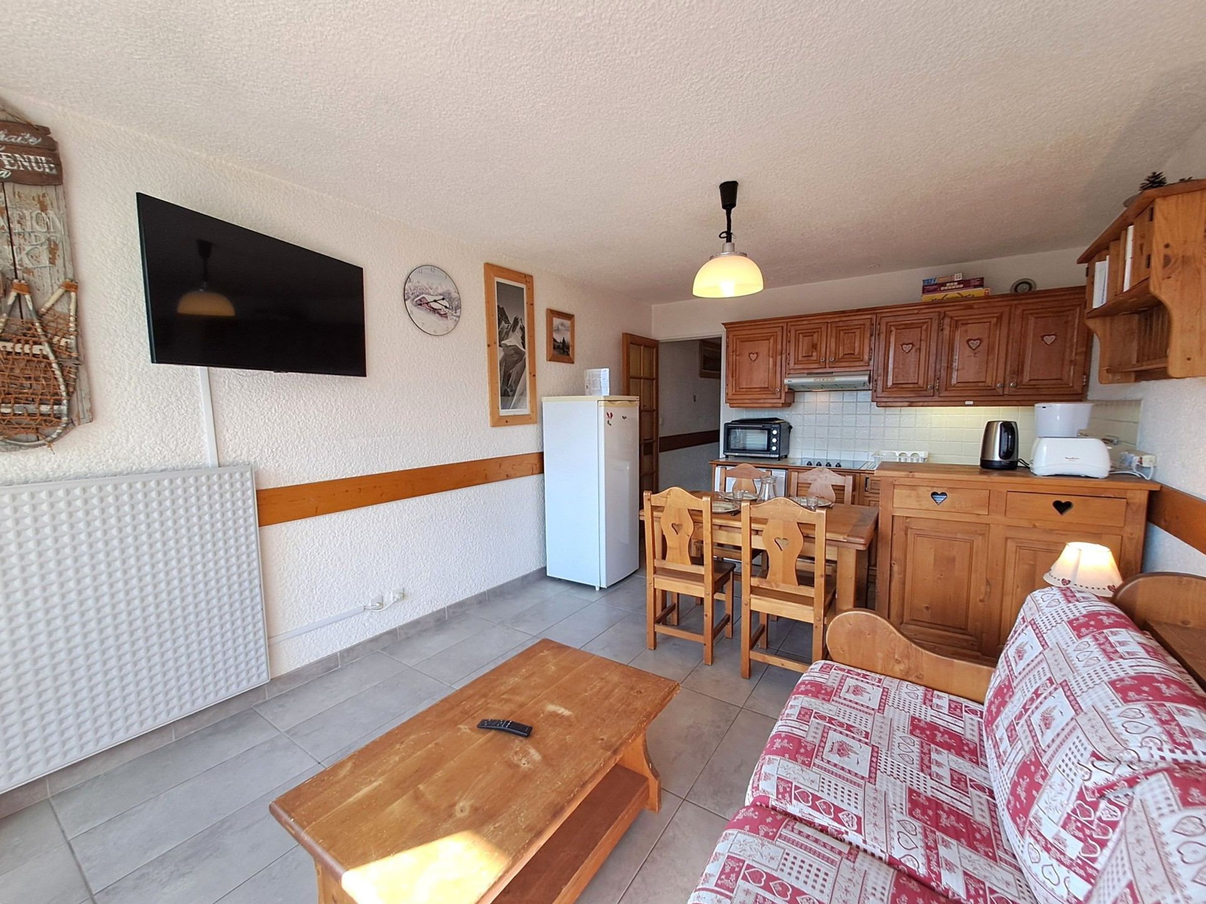 A compact living space with a kitchenette, a dining area, and a seating area with a sofa and a table.