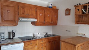 A kitchen with wooden cabinets, a stainless steel sink, a coffee maker, and a dishwasher.