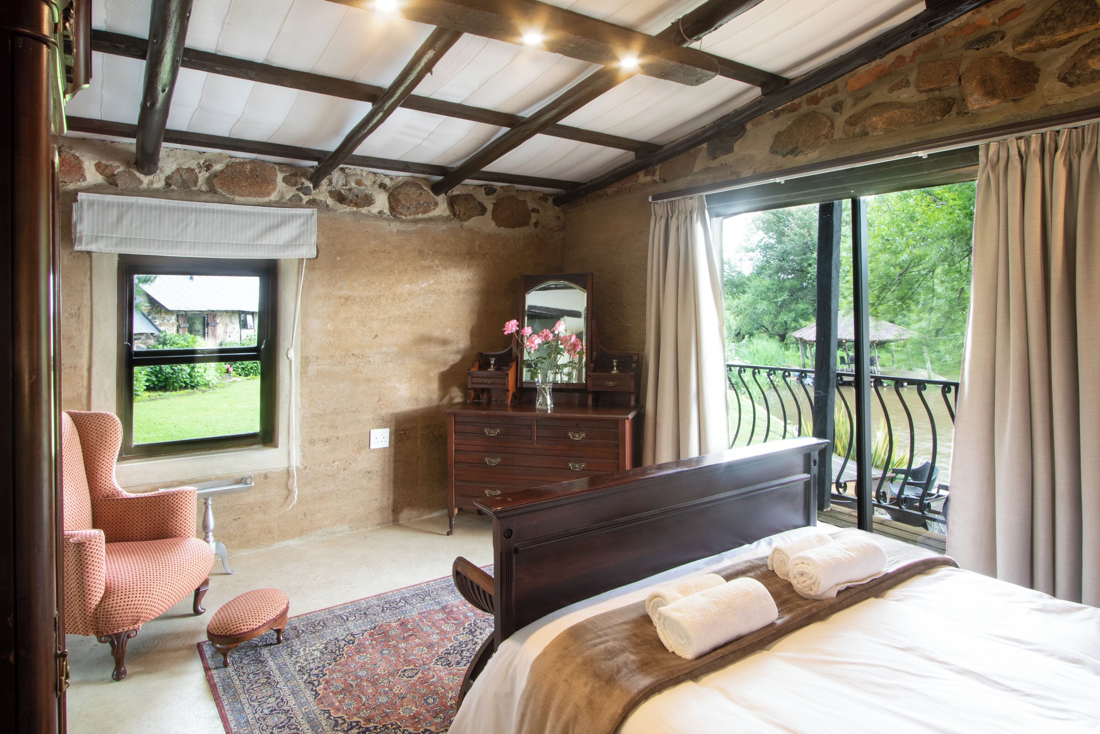 Un dormitorio con una cama grande, un aparador, una silla y una ventana con vistas a un jardín.
