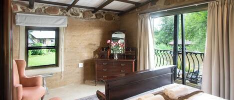 Un dormitorio con una cama grande, un aparador, una silla y una ventana con vistas a un jardín.
