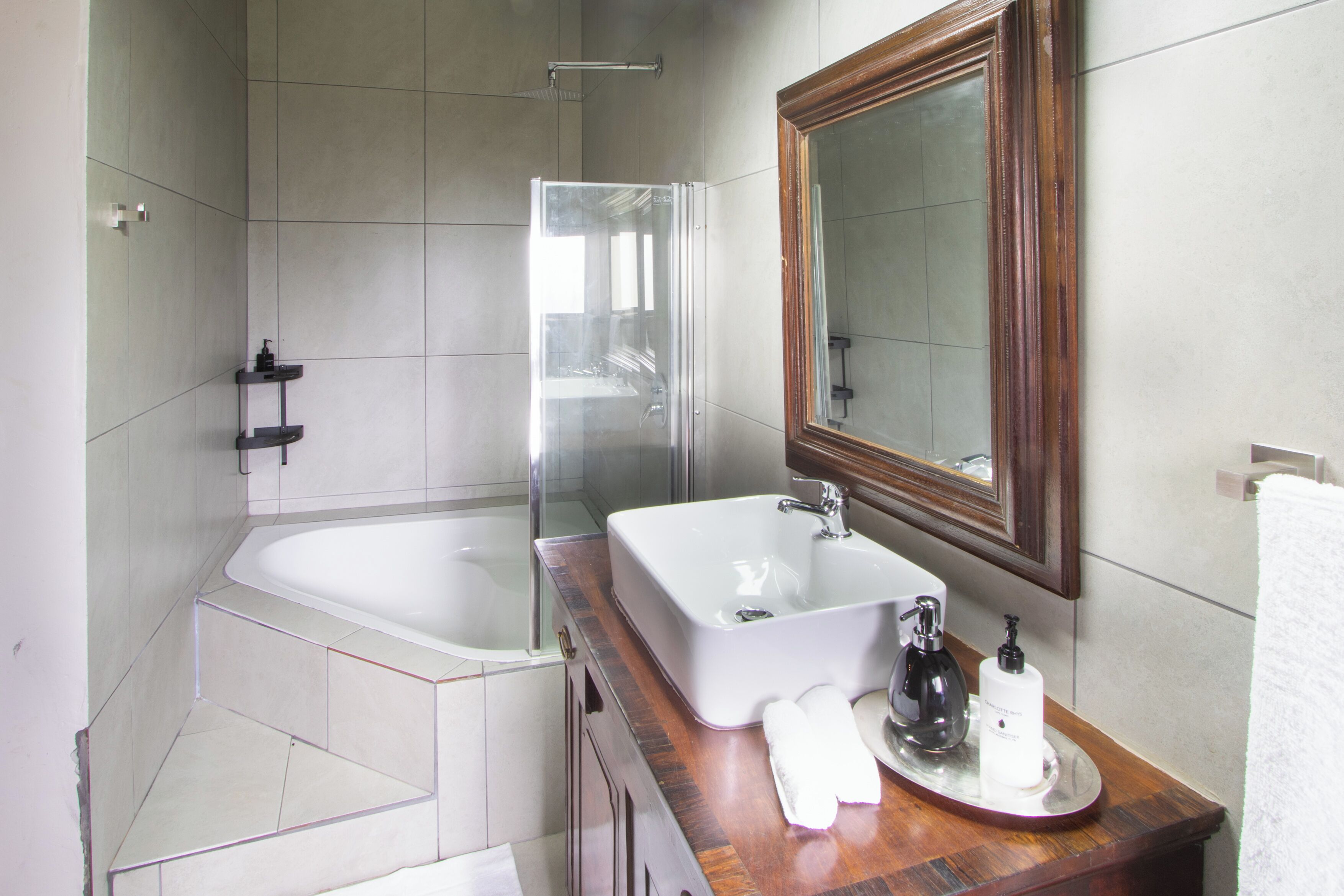 Un baño moderno con bañera, un espejo grande y un mueble de tocador de madera.