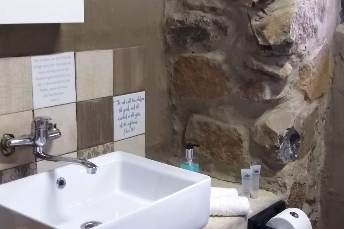A bathroom with a white sink, a framed picture on the wall, and a stone accent wall.