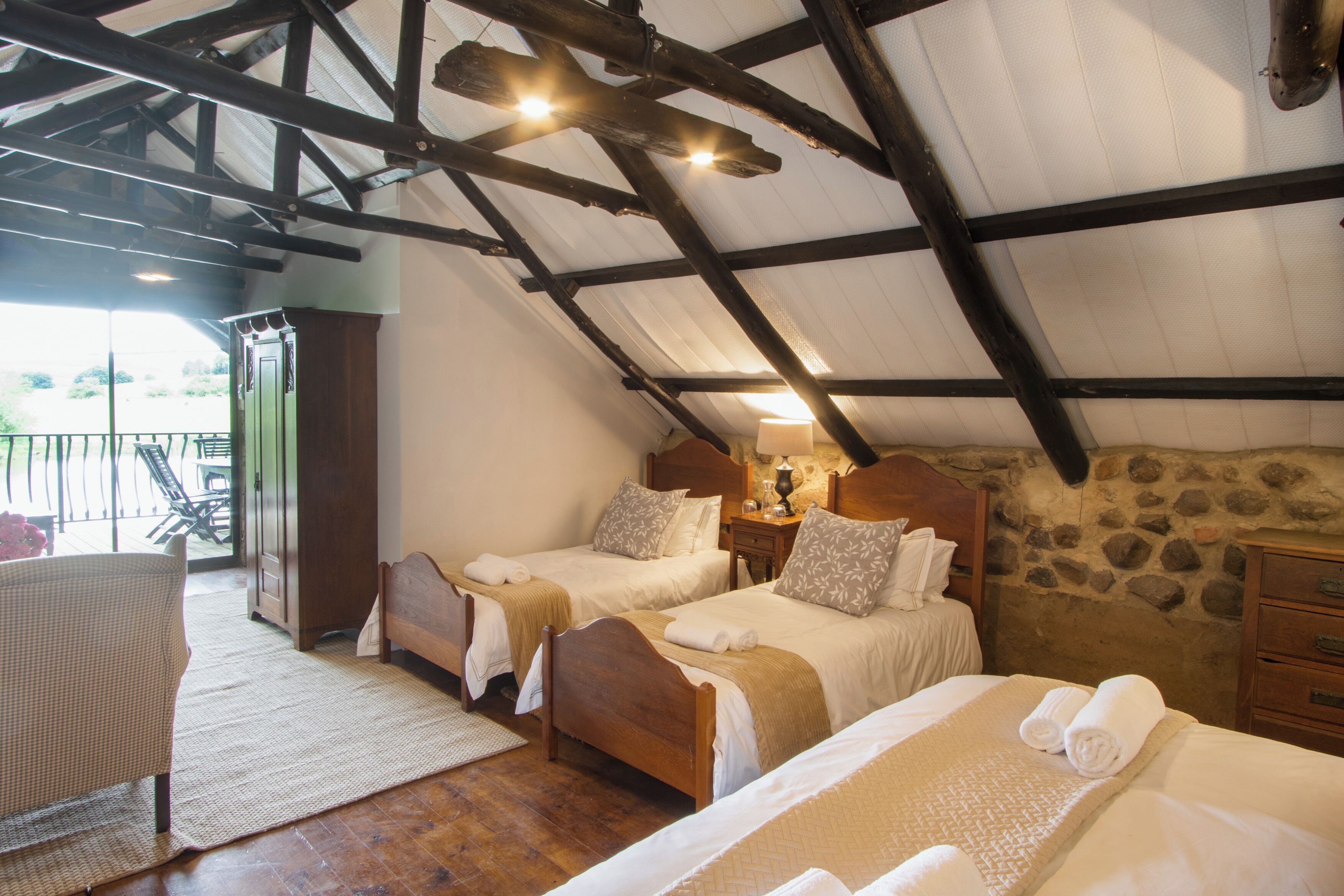 Camera da letto con due letti, soffitto in legno e parete in pietra.