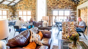 A rustic interior with stone walls, leather seating, and a variety of tables and chairs. - Flitwick Ranch (Greater Kokstad)