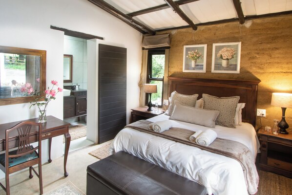 Une chambre bien éclairée, avec un grand lit, des tables de chevet, un bureau et une chaise.
